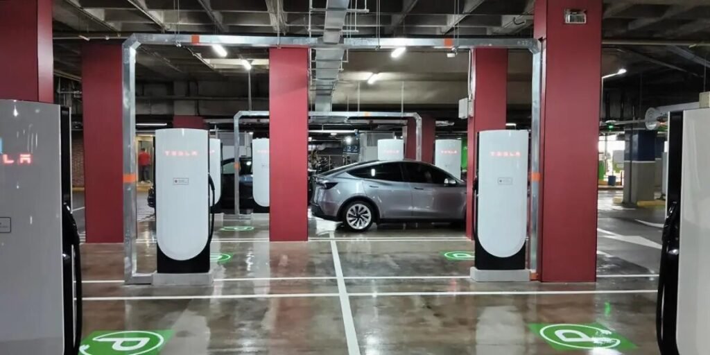 Estación Supercharger de Tesla en el parqueadero del Centro Comercial Andino de Bogotá, con un Tesla Model Y plateado cargando entre los postes