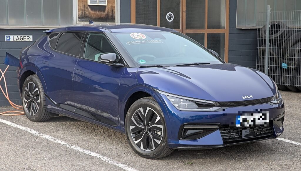 Kia EV6 GT-Line eléctrico conectado a un cargador, visto de tres cuartos delantero